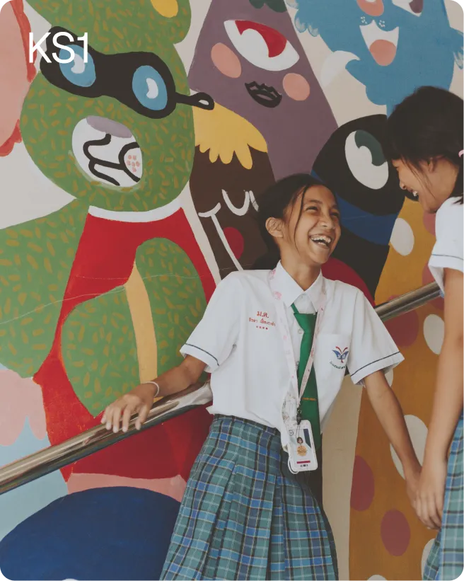 Students laughing in front of a colorful school mural